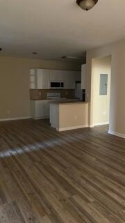 a view of kitchen and empty room with wooden floor