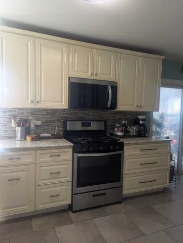 a kitchen with granite countertop white cabinets a stove a sink and dishwasher