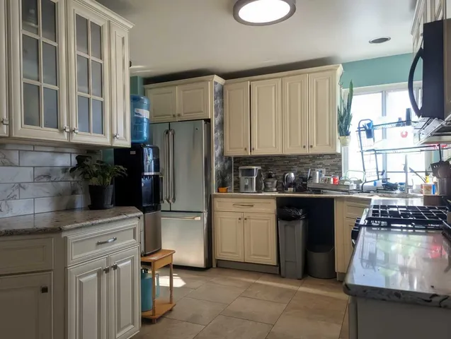 a kitchen with kitchen island granite countertop a refrigerator stove top oven and sink