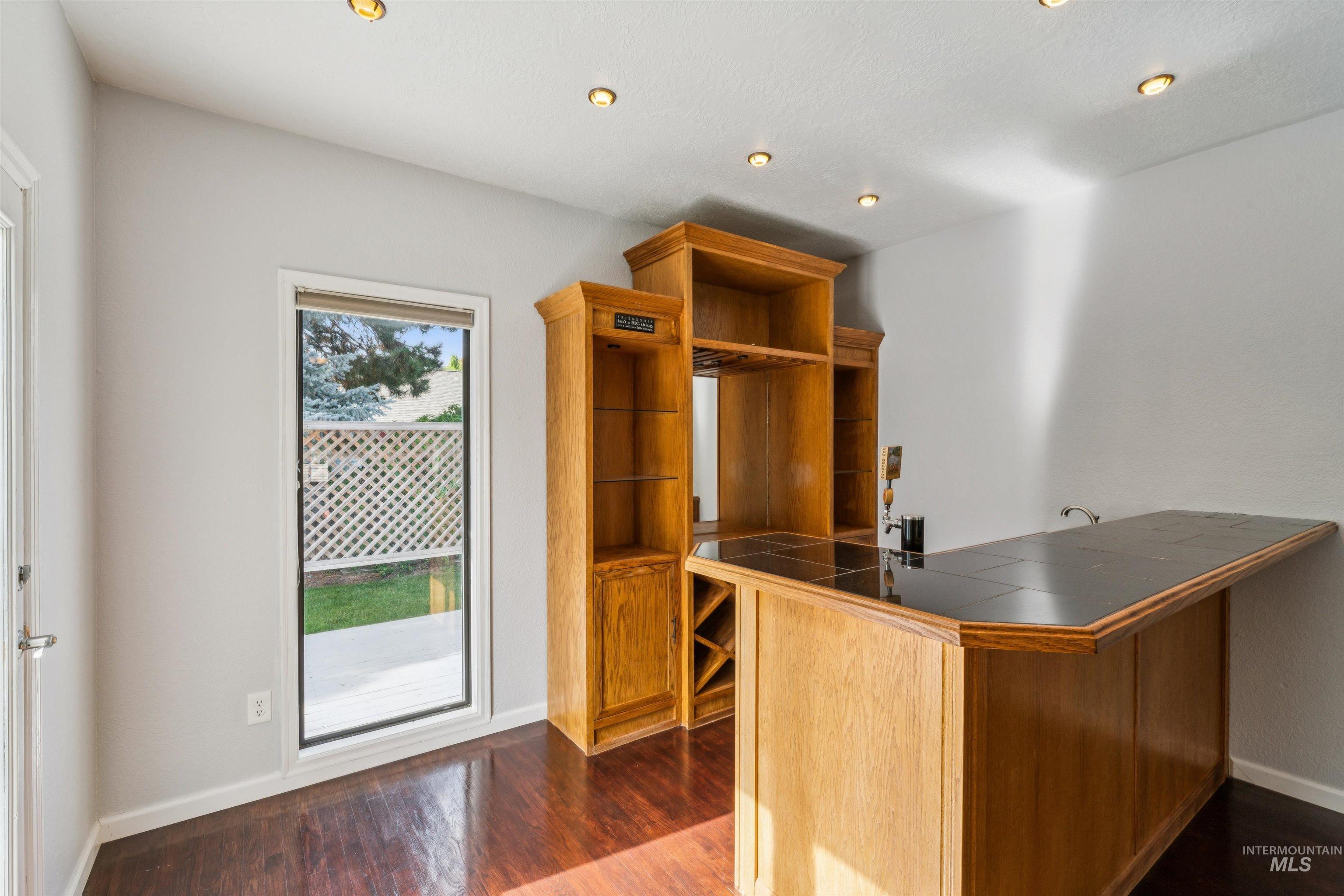 9831 West Ripley Street Boise, ID 83704 - Photo 7 of 47 Spacious interior featuring dark wood-finish flooring, a built-in wet bar with wooden cabinetry, a grand staircase with white balusters and dark wood handrails, a vaulted ceiling, and recessed lighting