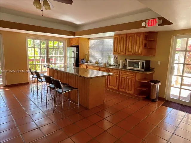 a dining hall with stainless steel appliances granite countertop a stove a kitchen island a dining table and chairs with the granite countertops