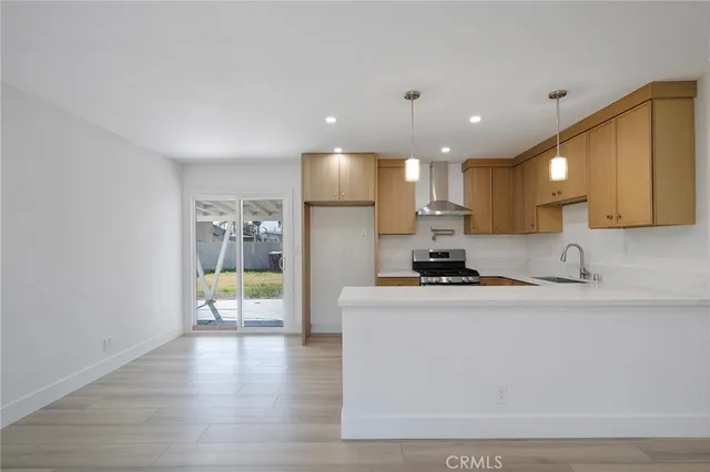 a view of a kitchen with kitchen island a sink wooden floor and a counter top space