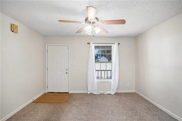 an empty room with windows and fan