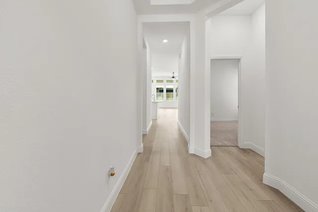 an empty room with wooden floor chandelier and windows