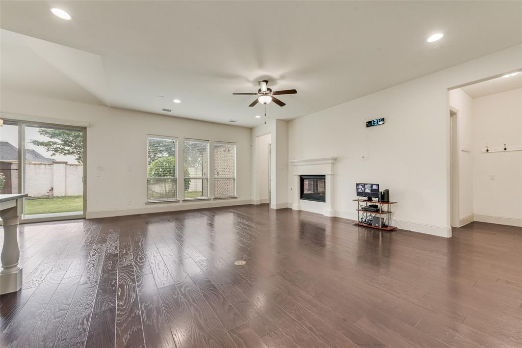 2021 Calisto Way Allen, TX 75013 - Photo 12 of 34 Spacious living area featuring rich wood-finish flooring, a contemporary fireplace with a classic mantel, and multiple windows providing abundant natural light