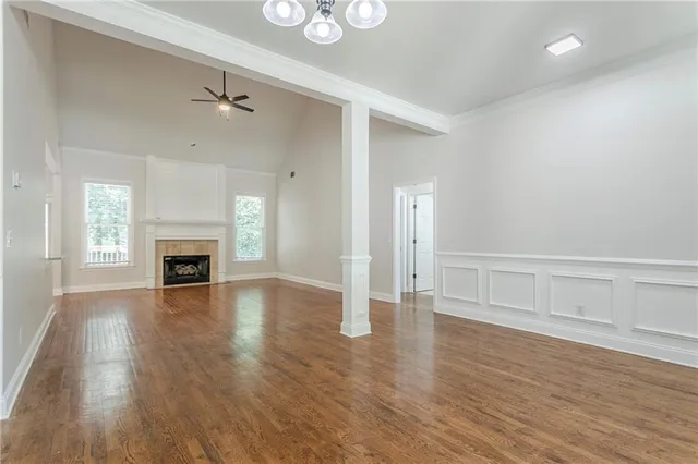 an empty room with wooden floor fireplace and windows