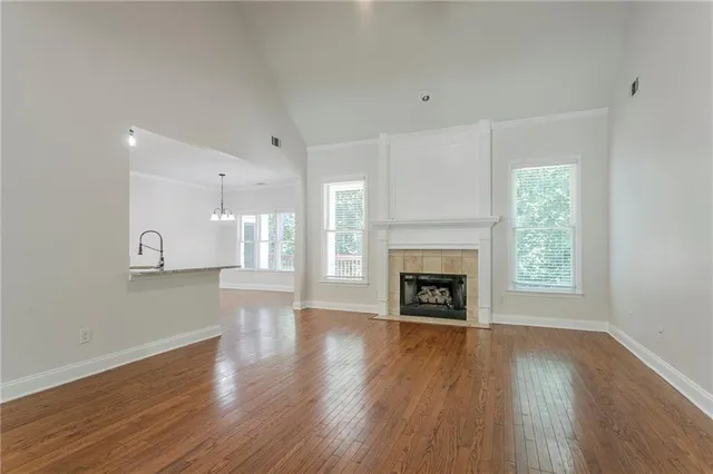 a view of an empty room with wooden floor fireplace and a window