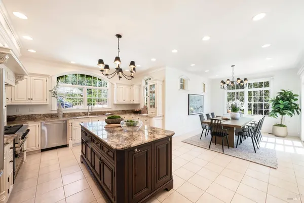 a kitchen with a stove top oven a sink dishwasher and a dining table with chairs