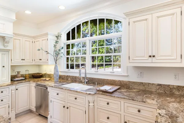 a kitchen with granite countertop white cabinets and window