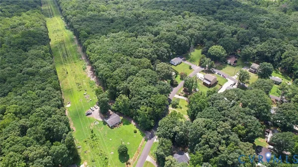 an aerial view of residential houses with outdoor space and trees all around