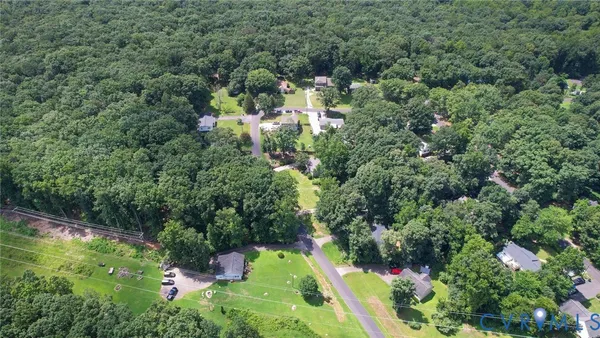 an aerial view of residential house with outdoor space and trees all around