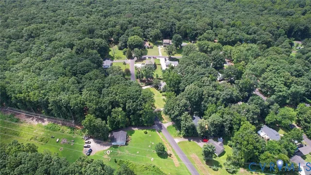 an aerial view of residential house with outdoor space and trees all around