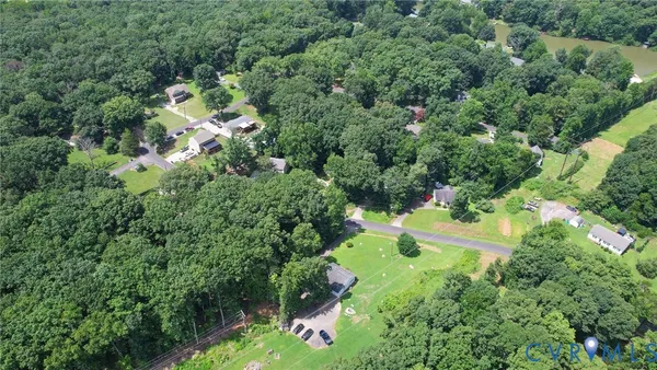 an aerial view of residential house with outdoor space and trees all around