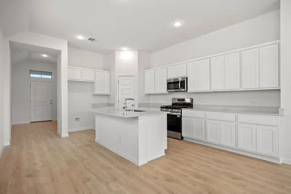a kitchen with granite countertop white cabinets and stainless steel appliances