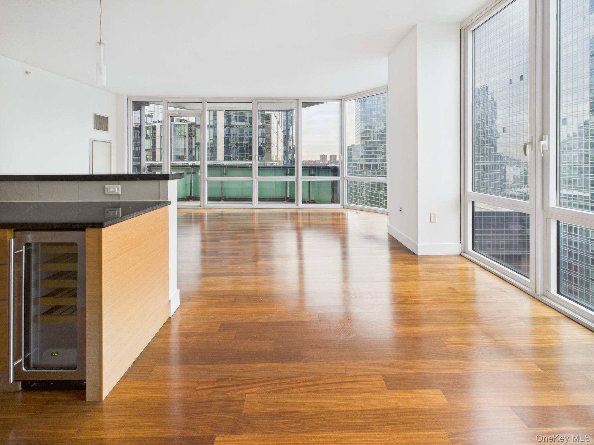 10 West End Avenue, Unit 20B Manhattan, NY 10023 - Photo 11 of 41 Unfurnished room featuring expansive windows, light wood finished floors, and beverage cooler