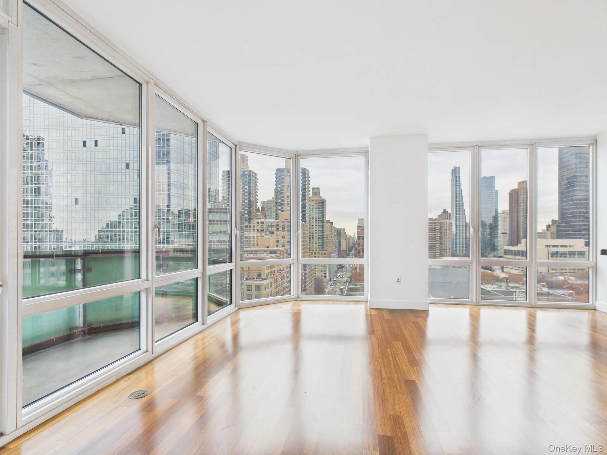 10 West End Avenue, Unit 20B Manhattan, NY 10023 - Photo 12 of 41 Empty room featuring expansive windows, wood finished floors, healthy amount of natural light, and a view of skyline