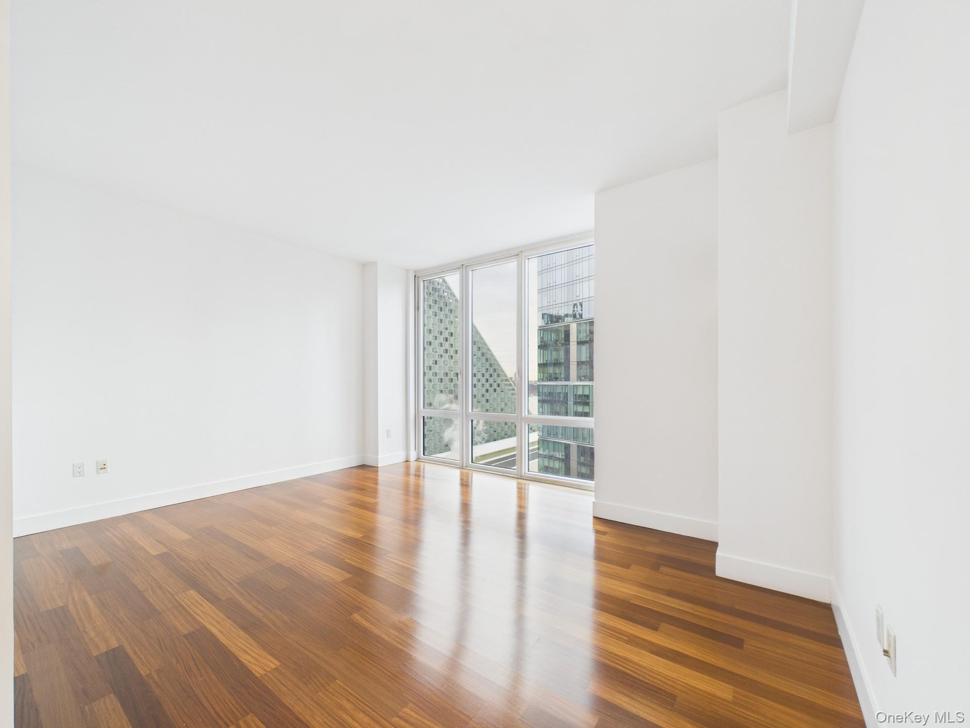10 West End Avenue, Unit 20B Manhattan, NY 10023 - Photo 14 of 41 Empty room with dark wood finished floors and floor to ceiling windows