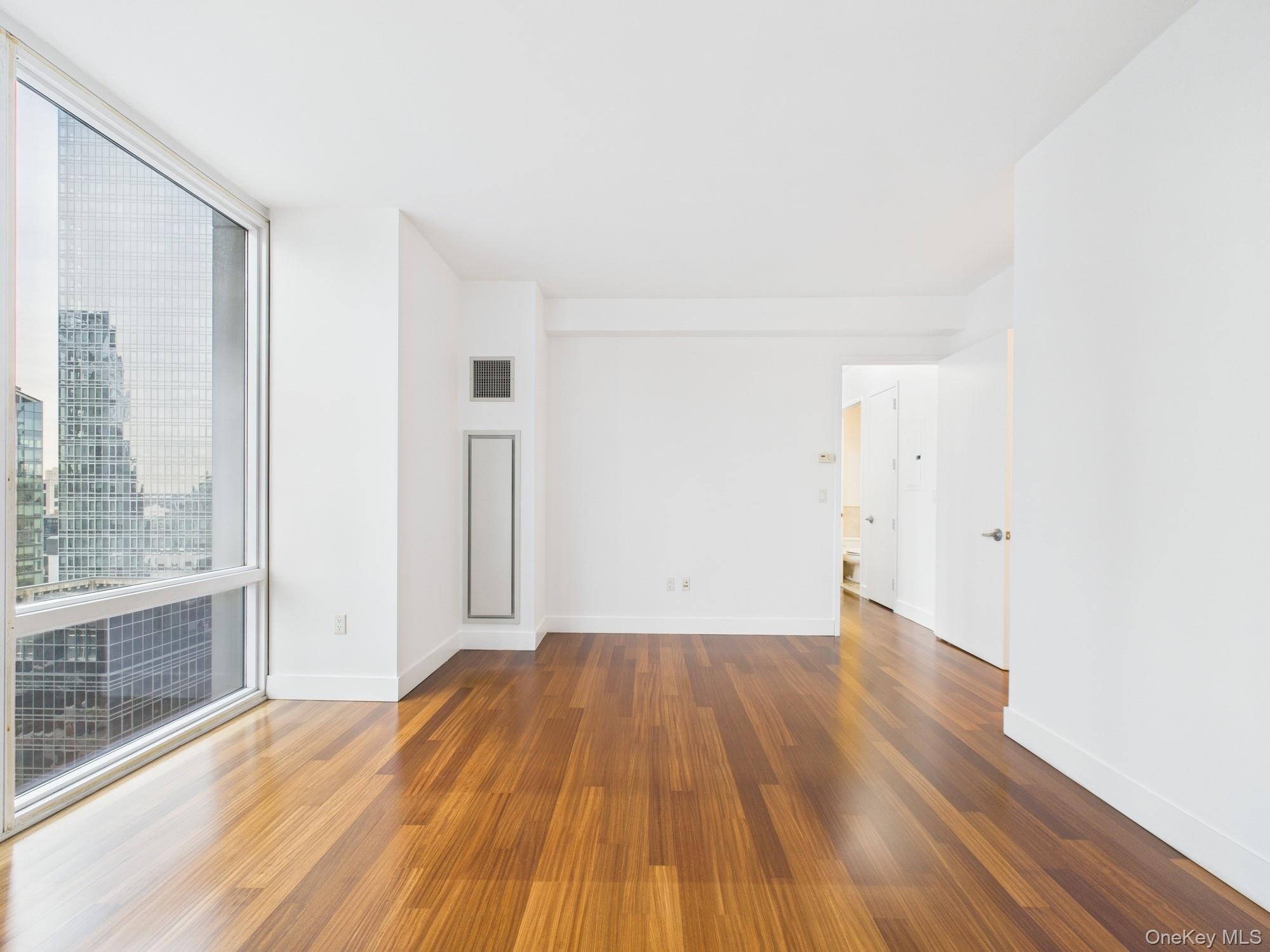 10 West End Avenue, Unit 20B Manhattan, NY 10023 - Photo 16 of 41 Unfurnished room featuring a wall of windows and dark wood finished floors
