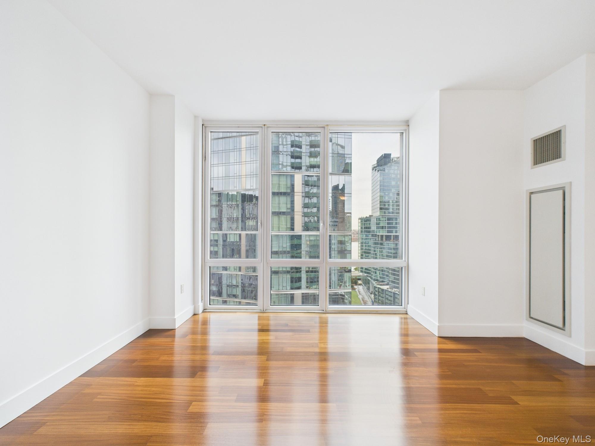10 West End Avenue, Unit 20B Manhattan, NY 10023 - Photo 17 of 41 Empty room featuring floor to ceiling windows and wood finished floors