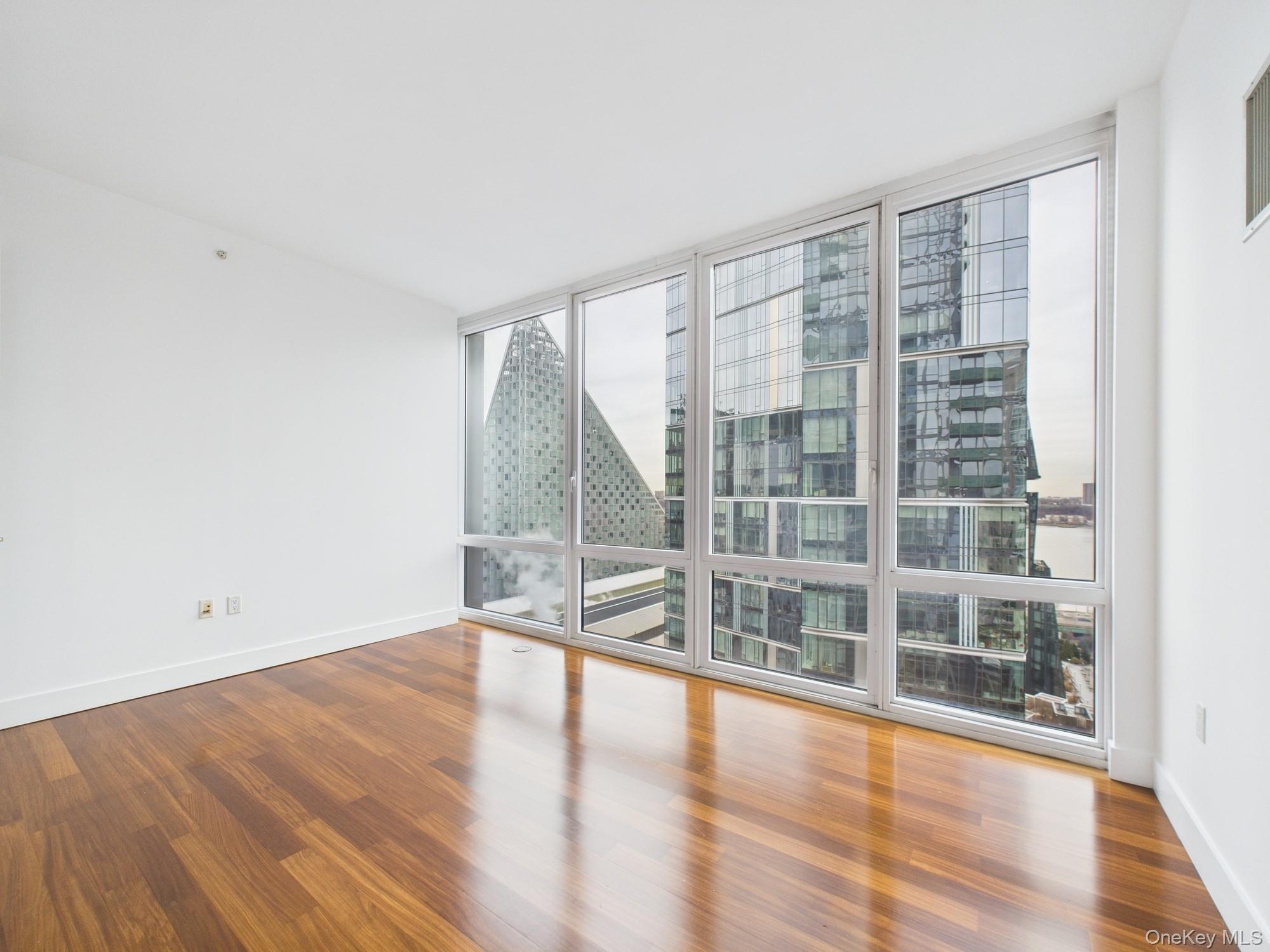 10 West End Avenue, Unit 20B Manhattan, NY 10023 - Photo 23 of 41 Spare room featuring dark wood-type flooring and floor to ceiling windows