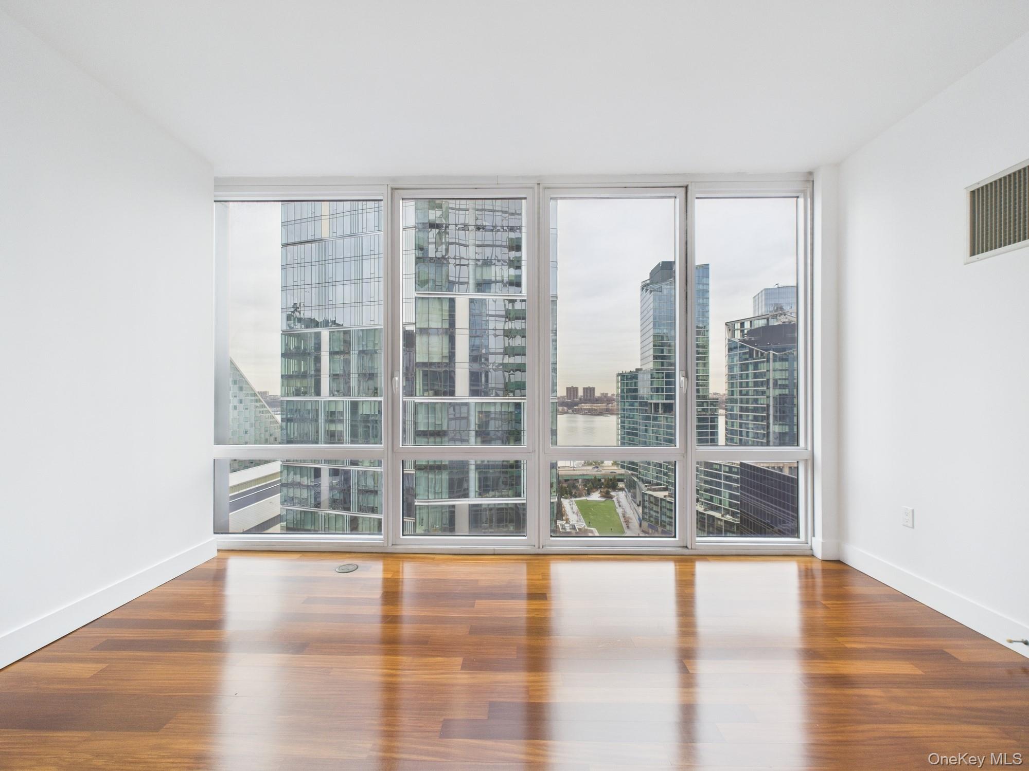 10 West End Avenue, Unit 20B Manhattan, NY 10023 - Photo 25 of 41 Spare room with floor to ceiling windows, plenty of natural light, wood finished floors, and a city view