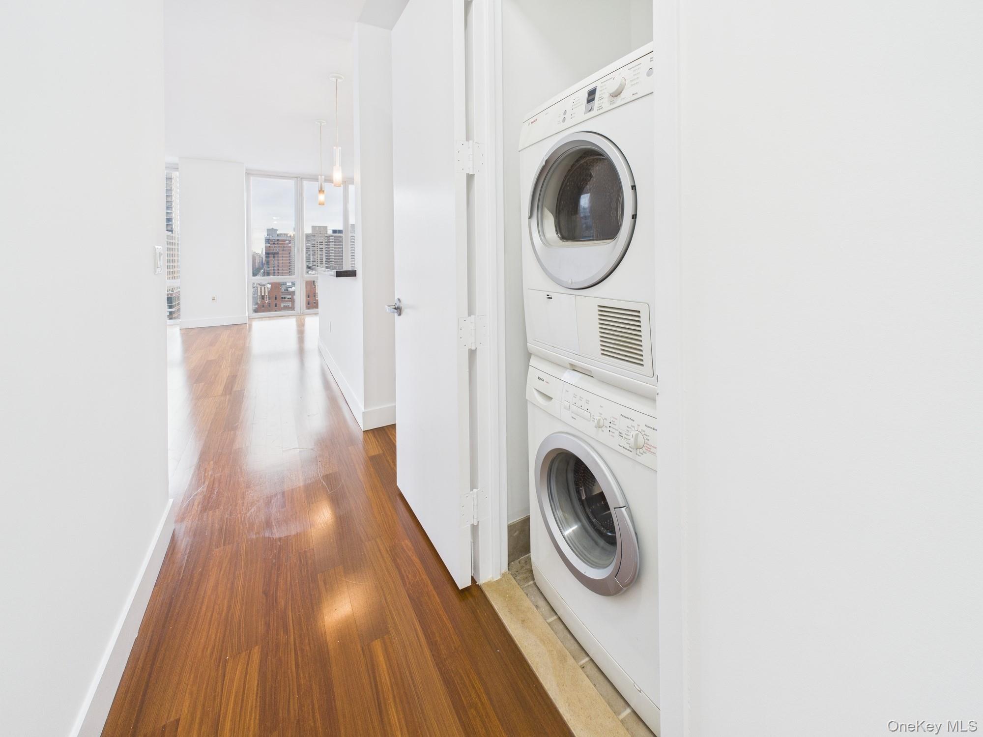 10 West End Avenue, Unit 20B Manhattan, NY 10023 - Photo 30 of 41 Laundry room with dark wood finished floors and estacked washer and dryer
