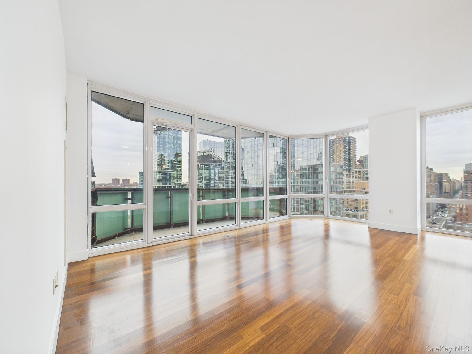 10 West End Avenue, Unit 20B Manhattan, NY 10023 - Photo 8 of 41 Unfurnished room featuring a view of skyline, wood finished floors, and a wall of windows