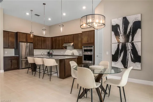 a kitchen with kitchen island a dining table chairs stainless steel appliances and cabinets