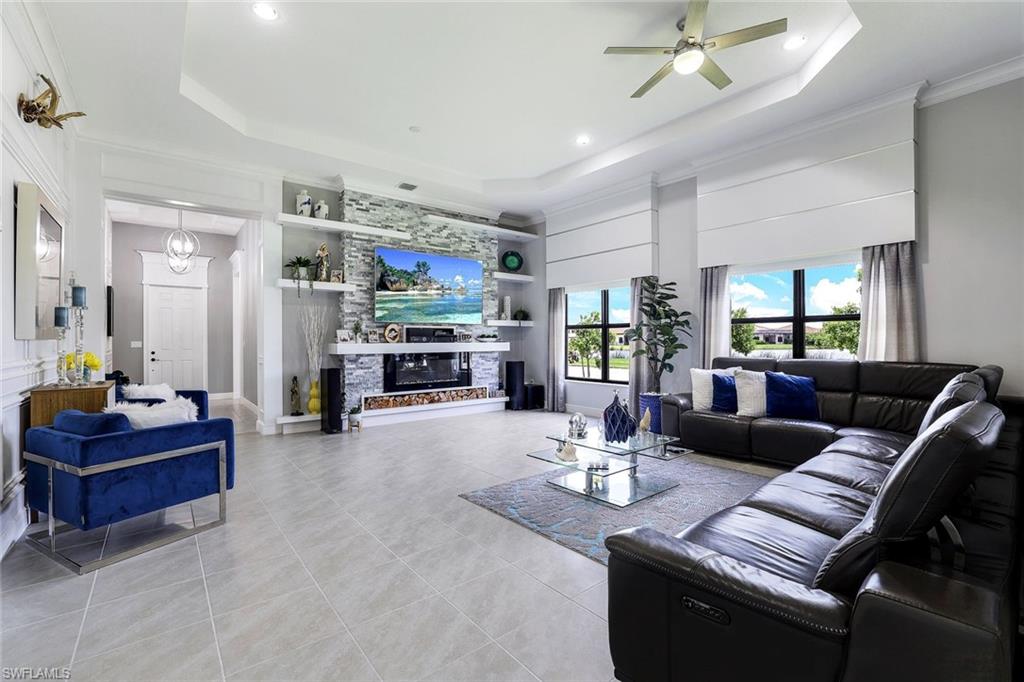 4795 Rosetta Terrace Immokalee, FL 34142 - Photo 1 of 27 Living area with a fireplace, crown molding, ceiling fan, a tray ceiling, and light tile patterned floors