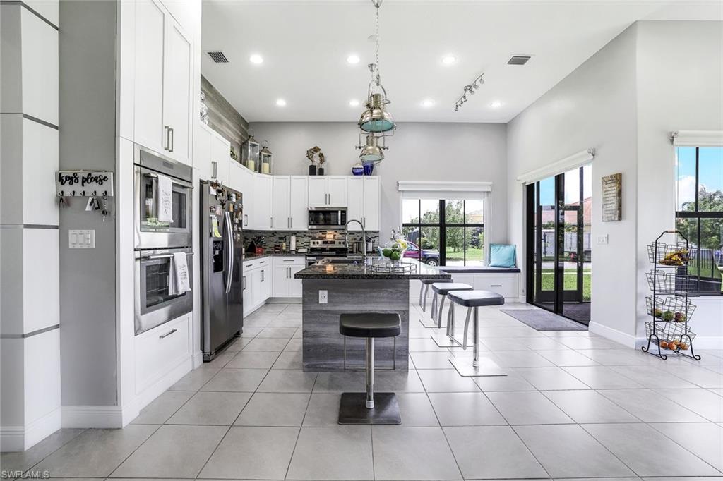 4795 Rosetta Terrace Immokalee, FL 34142 - Photo 4 of 27 Kitchen with white cabinetry, stainless steel appliances, a breakfast bar area, a center island with sink, and a high ceiling