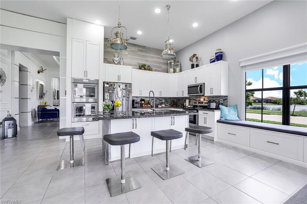 4795 Rosetta Terrace Immokalee, FL 34142 - Photo 5 of 27 Kitchen with white cabinets, pendant lighting, a kitchen bar, appliances with stainless steel finishes, and a center island with sink