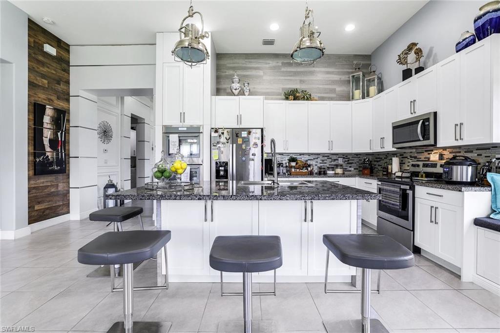4795 Rosetta Terrace Immokalee, FL 34142 - Photo 6 of 27 Kitchen featuring appliances with stainless steel finishes, wood walls, white cabinets, a kitchen breakfast bar, and backsplash