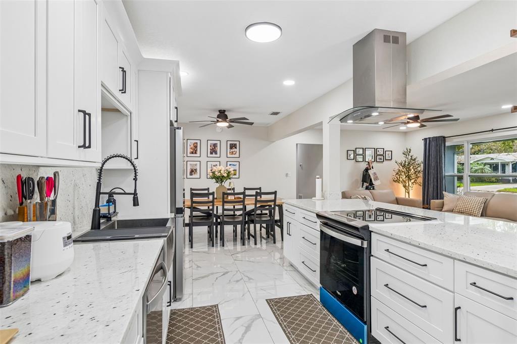 1618 Barry Road Clearwater, FL 33756 - Photo 18 of 71 a kitchen with stainless steel appliances granite countertop a stove a sink dishwasher and white cabinets with wooden floor
