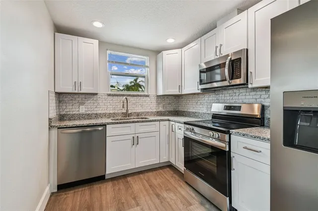 a kitchen with stainless steel appliances granite countertop a stove a sink and a microwave