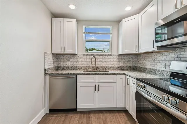 a kitchen with stainless steel appliances granite countertop a sink stove and cabinets