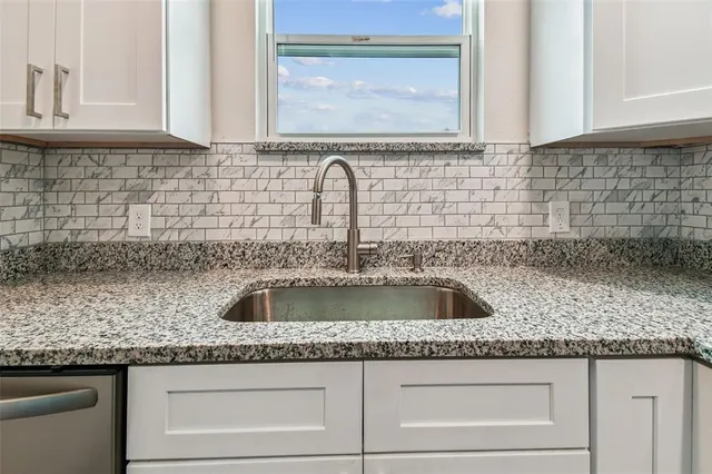 a kitchen with granite countertop a sink and a wooden cabinets
