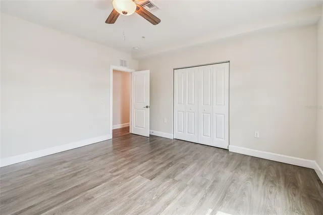 an empty room with wooden floor ceiling fan