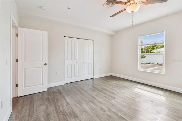 a view of an empty room with window and wooden floor
