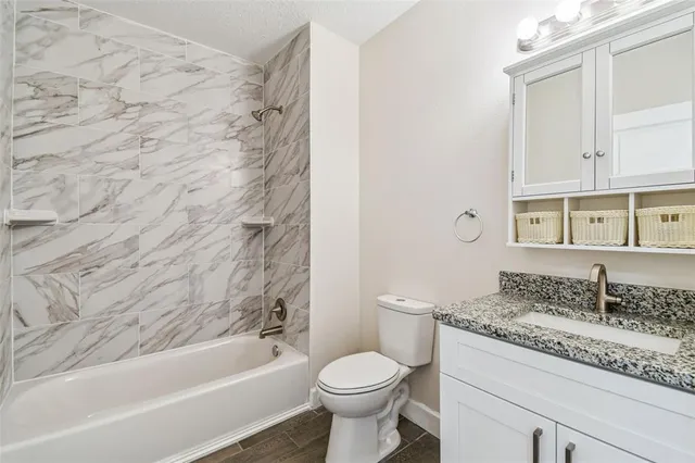 a bathroom with a granite countertop toilet a sink and a bathtub