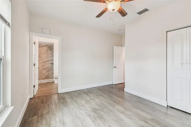 an empty room with a hardwood and ceiling fan