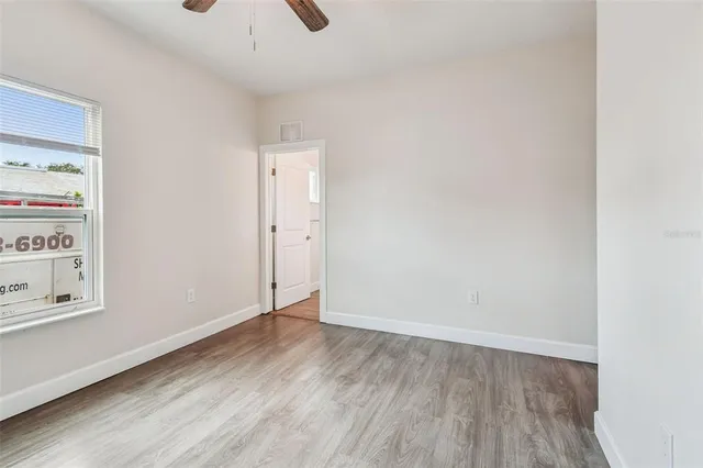 an empty room with a hardwood and ceiling fan