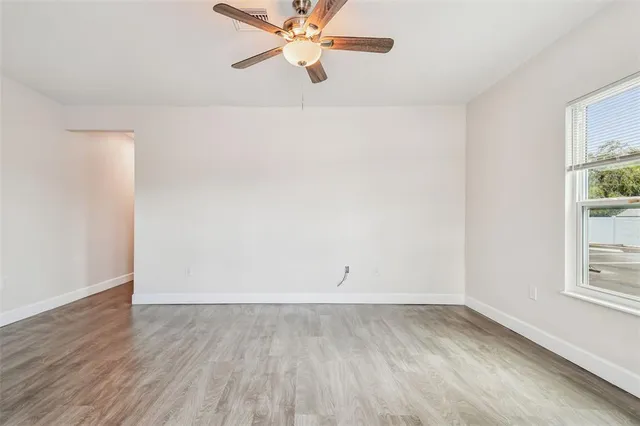 an empty room with a window and a ceiling fan