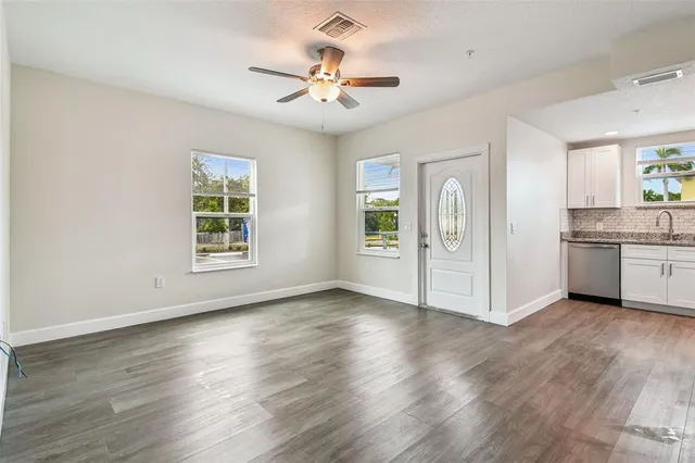 a view of an empty room with window and wooden floor