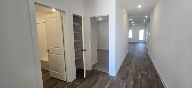 a view of a hallway with wooden floor and closet