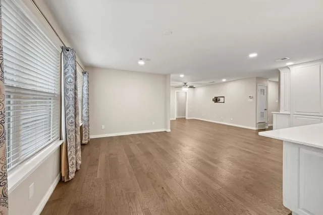 an empty room with wooden floor and windows