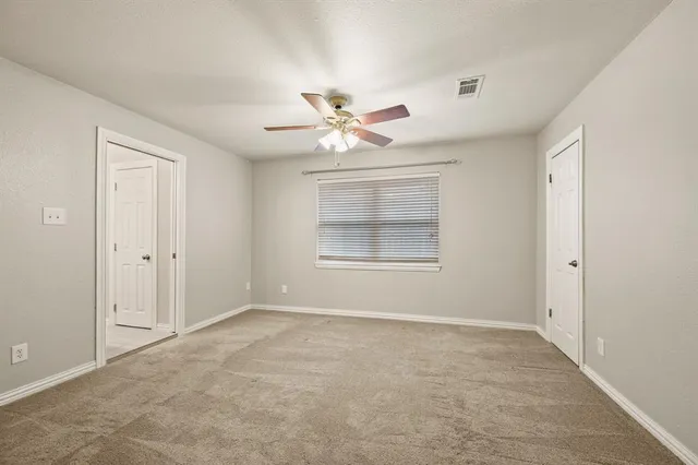 a view of an empty room with a ceiling fan and window