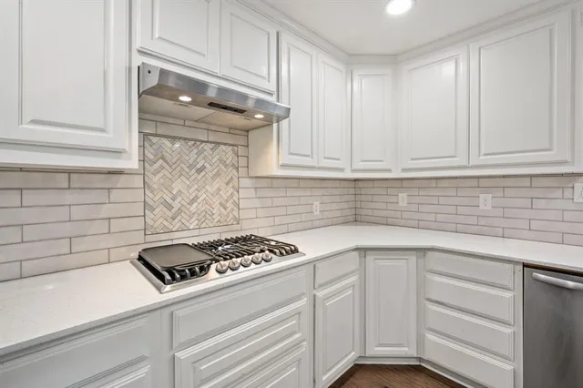 a kitchen with white cabinets and appliances