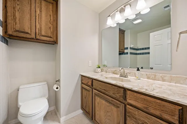 a bathroom with a granite countertop toilet sink and mirror