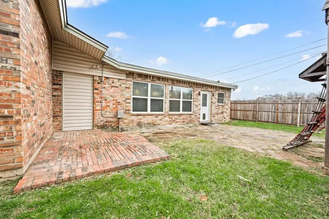 a view of a house with backyard and wooden fence
