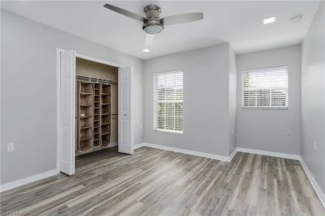 a view of empty room with wooden floor and fan
